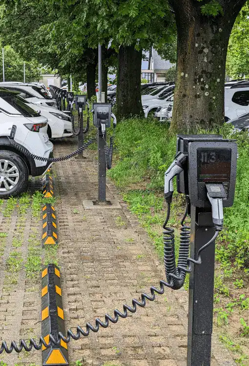Elektrische Ladestationen für E-Fahrzeuge im Freien, umgeben von Bäumen.